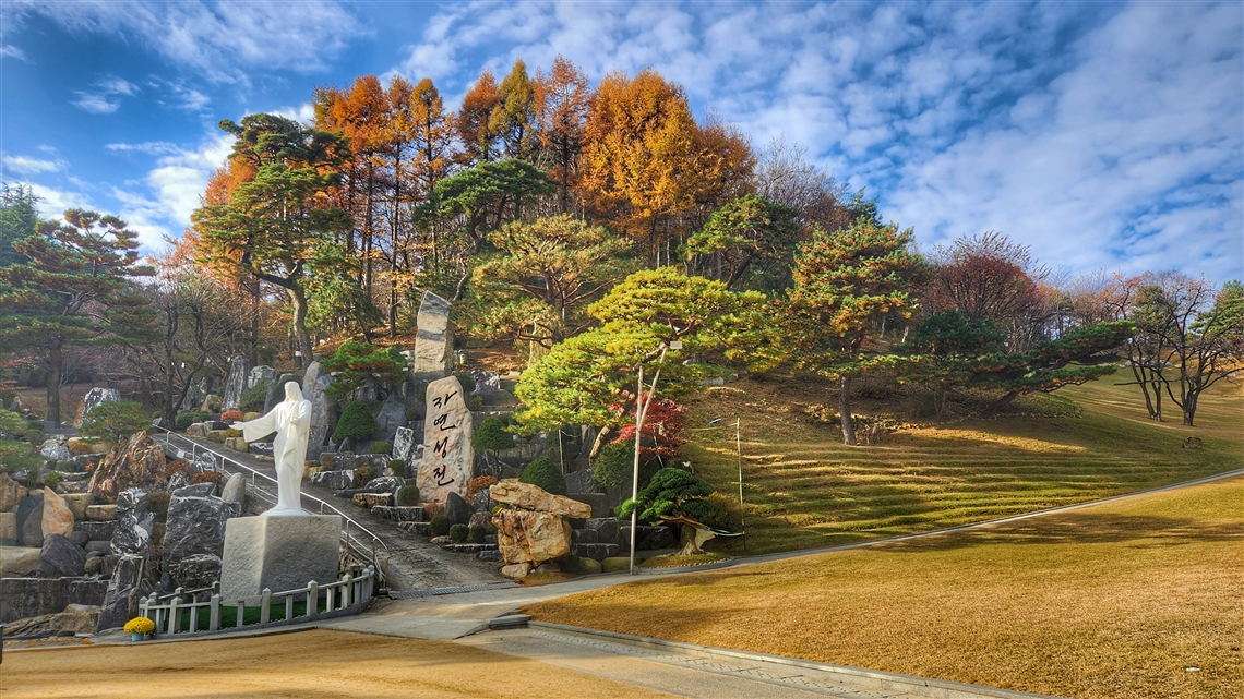 잔디밭 앞에 설치된 예수님상과 주변 자연 환경, 월명동 자연성전